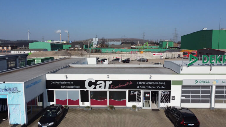 Fassade des Car Koschmetik Smart Repair-Centers mit Fahrzeugen auf dem Parkplatz.