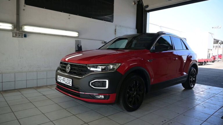 Roter Volkswagen T-Roc SUV steht in einer Werkstatt mit hellem Licht.
